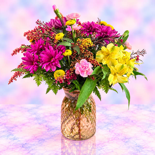 Colorful bouquet of pink, yellow, and purple flowers in a gold vase