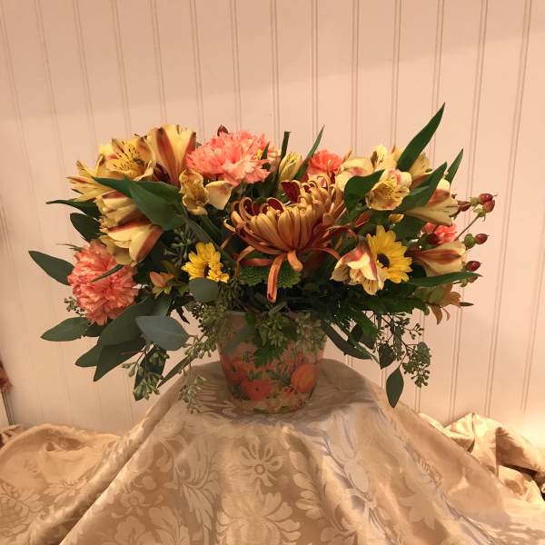 Mixed bouquet in a decorative vase with yellow, coral, and burgundy flowers
