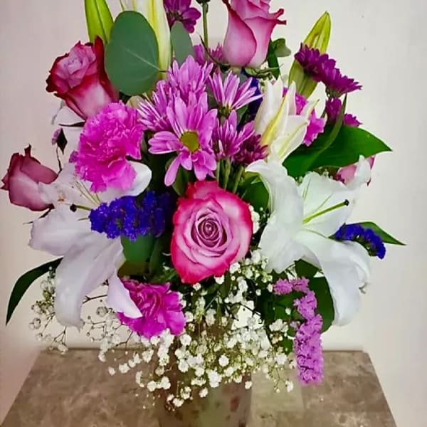 Bouquet of pink roses, white lilies, and purple flowers in a vase