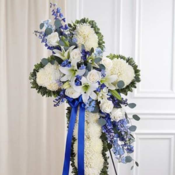 White floral standing cross with blue ribbon and accents