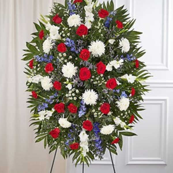 Standing funeral spray with red roses, white chrysanthemums, and blue flowers