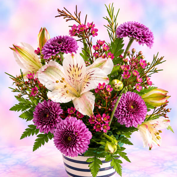 Purple chrysanthemums and white lilies in a striped vase