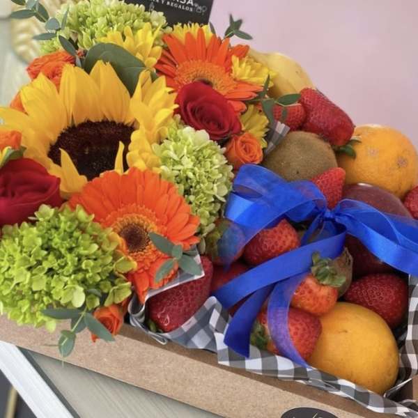 Bouquet with sunflowers, gerbera daisies, roses, and fruit in a box
