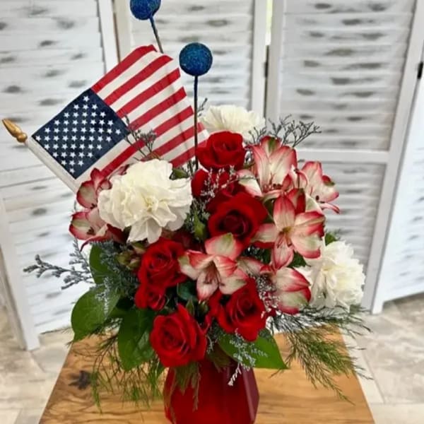 Red roses and white carnations in a vase with a small American flag