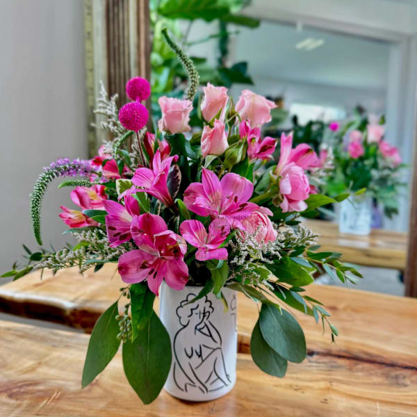 Pink flowers arranged in a white vase with a line drawing on it