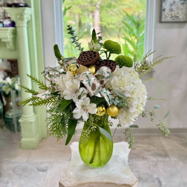 White flowers and green mums in a lime vase with gold ornaments and ribbon