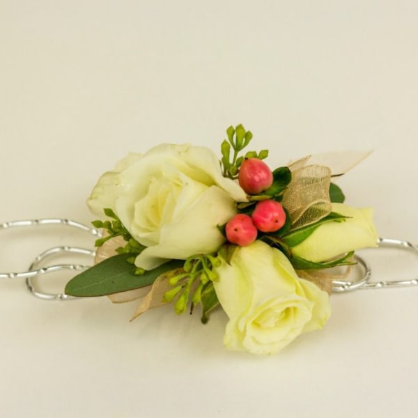 White rose corsage with pink berries and ribbon on a silver bracelet