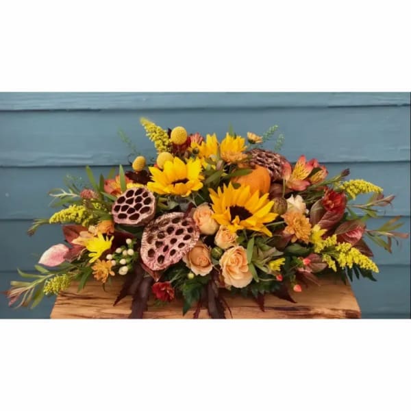 Autumn floral arrangement with sunflowers, peach roses, and lotus pods