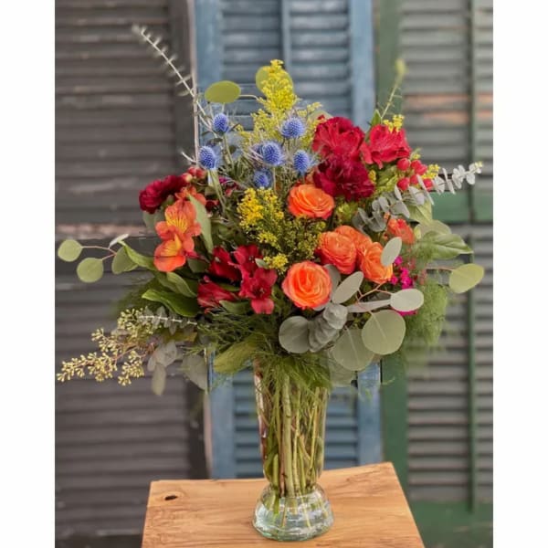 Mixed bouquet in a clear glass vase with orange, red, and blue flowers