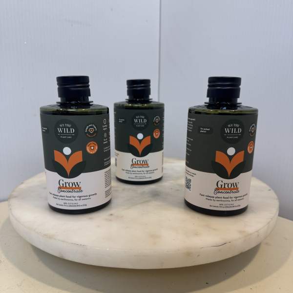 Three plant care bottles on a round white pedestal