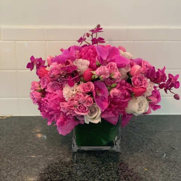 Pink and white floral arrangement in a square glass vase