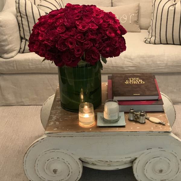 Large bouquet of deep red roses in a green vase on a coffee table