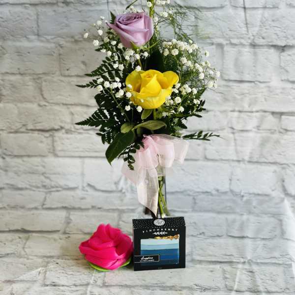 Tall bouquet of pink, lavender, and yellow roses with baby's breath and a ribbon