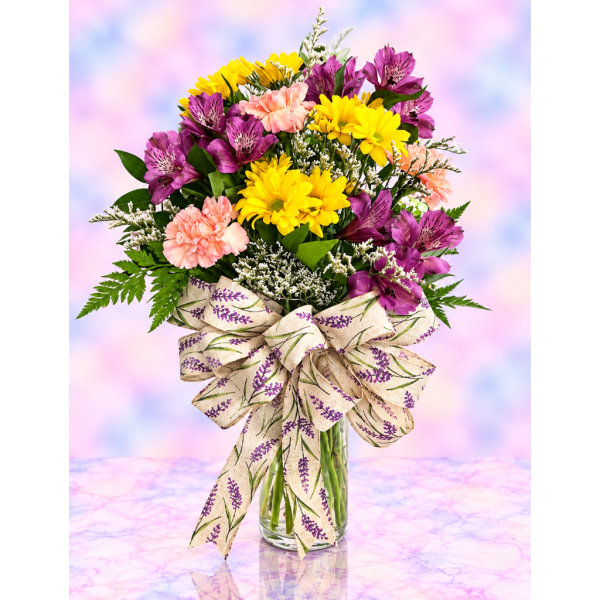 Bouquet of yellow daisies, purple alstroemeria, and pink carnations in a glass vase.