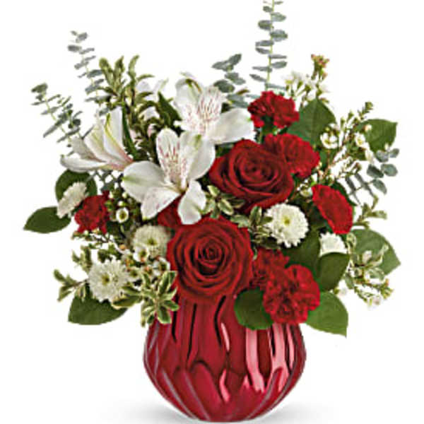 Red roses and white lilies arranged in a red glass vase