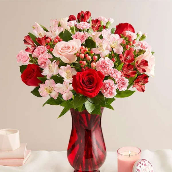 Bouquet of red and pink flowers in a red glass vase