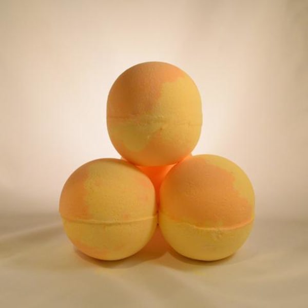 Three orange-yellow bath bombs stacked in a pyramid