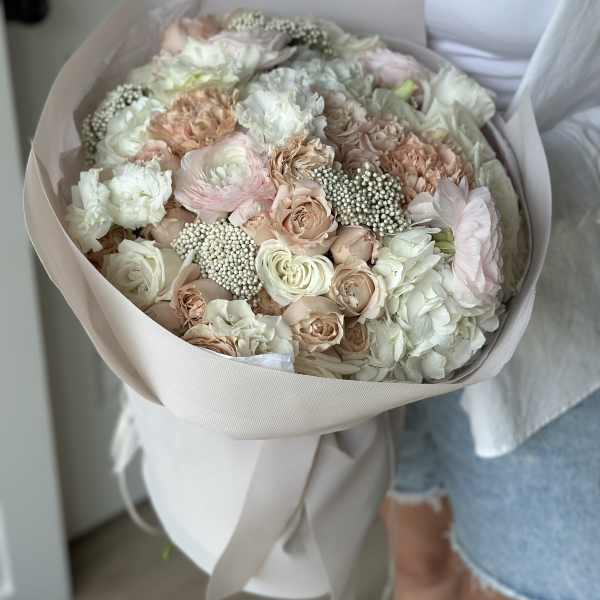 Large pastel bouquet of roses and carnations wrapped in pale paper