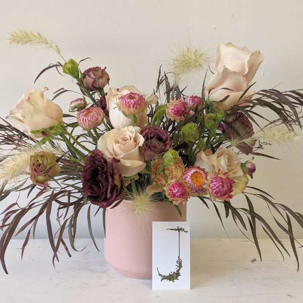Mixed bouquet of blush and burgundy flowers in a pink vase