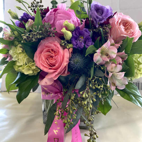 Mixed pink and purple bouquet in a clear glass vase with ribbon