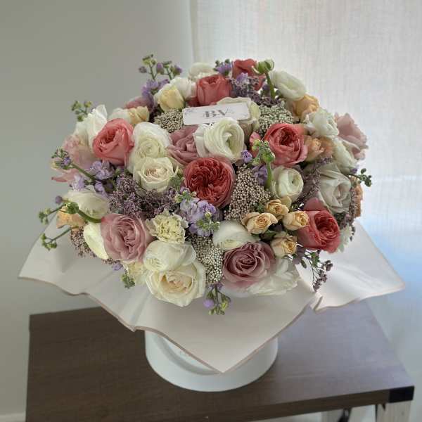 Large bouquet of pink, white, and peach roses with lavender accents