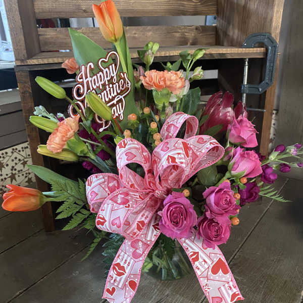 Pink and orange floral bouquet with a Valentine’s Day sign and ribbon