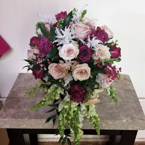 Bouquet of pink, cream, and burgundy roses with trailing white flowers
