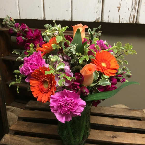Bright mixed bouquet in a glass vase with orange gerberas and pink carnations