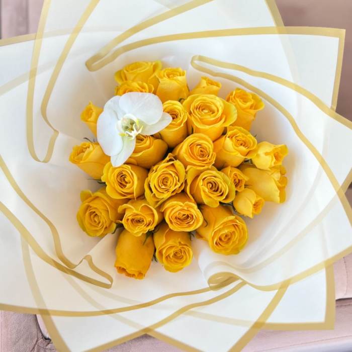 Yellow rose bouquet with a white orchid accent in white and gold wrap