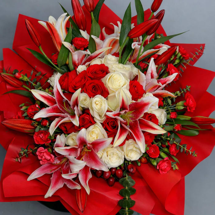 Bouquet of red and white roses with pink lilies wrapped in red paper