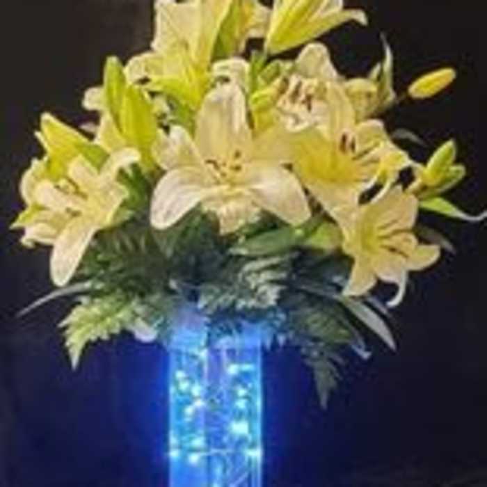 White and yellow lilies arranged in a tall blue vase