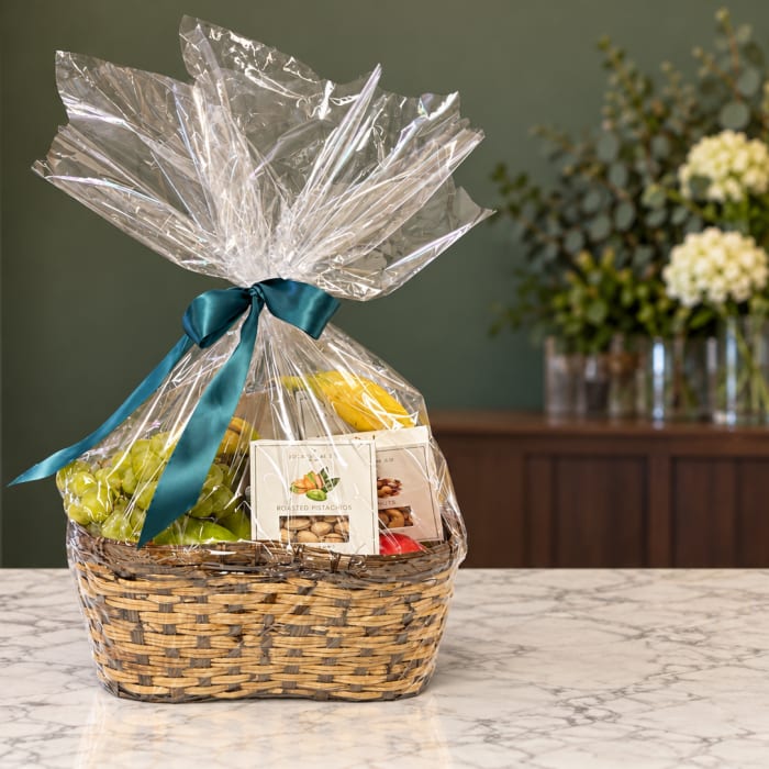 Gift basket with fruit and snack packages tied with a teal ribbon