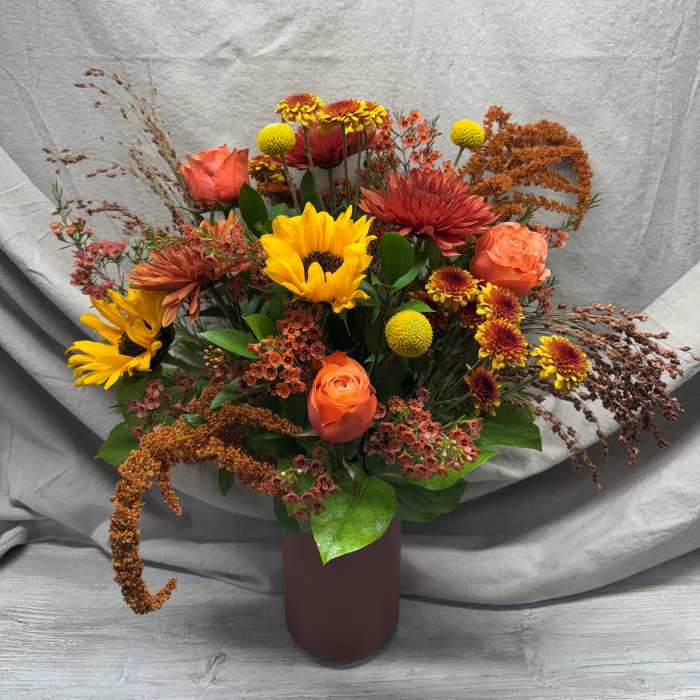 Autumn-toned arrangement with sunflowers, orange roses, and mums in a matte brown cylinder vase