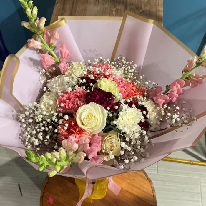 Bouquet of pink and cream flowers wrapped in pale paper