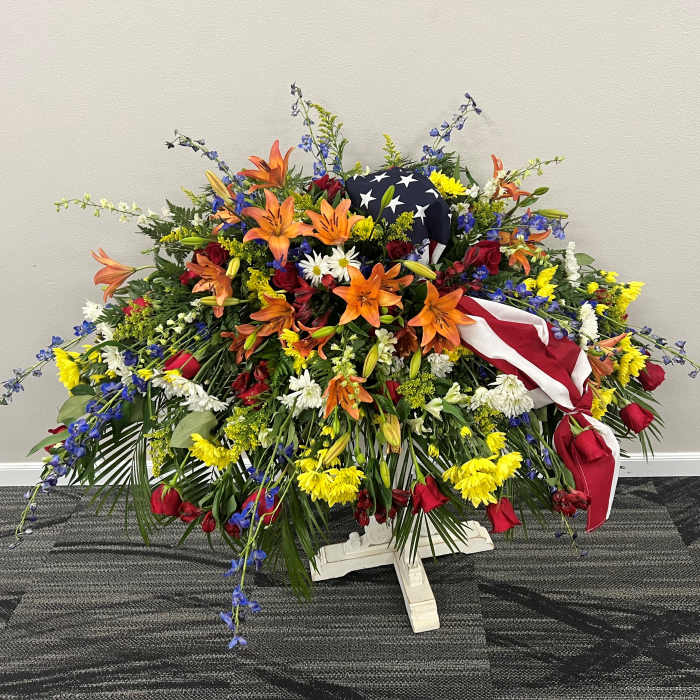 Large patriotic floral spray with red, white, and blue flowers and an American flag
