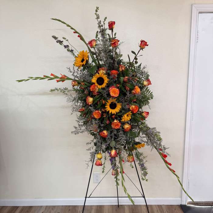 Tall floral spray with sunflowers and orange roses on a stand