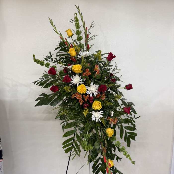 Tall standing floral spray with red and yellow roses and white daisies