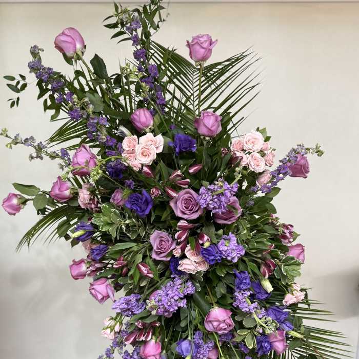 Tall floral spray with pink and purple roses and mixed blooms on a stand
