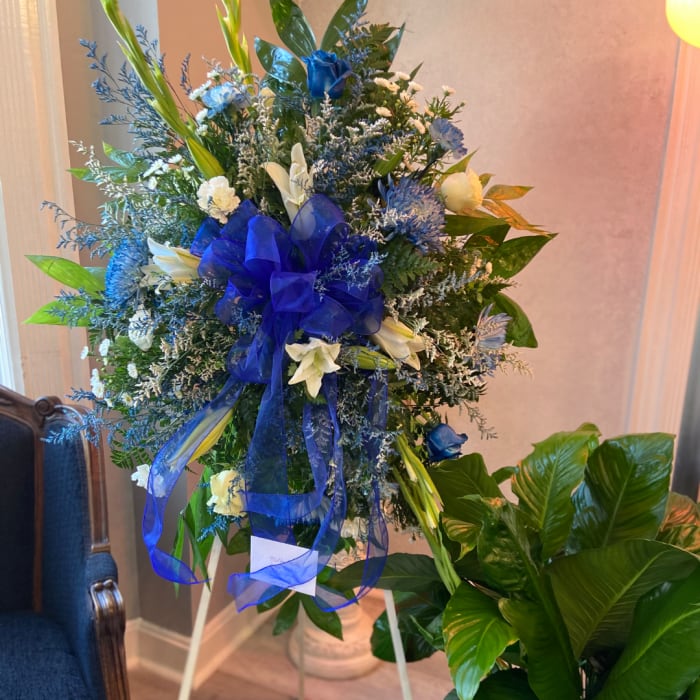 Blue and white floral standing spray with a large blue ribbon