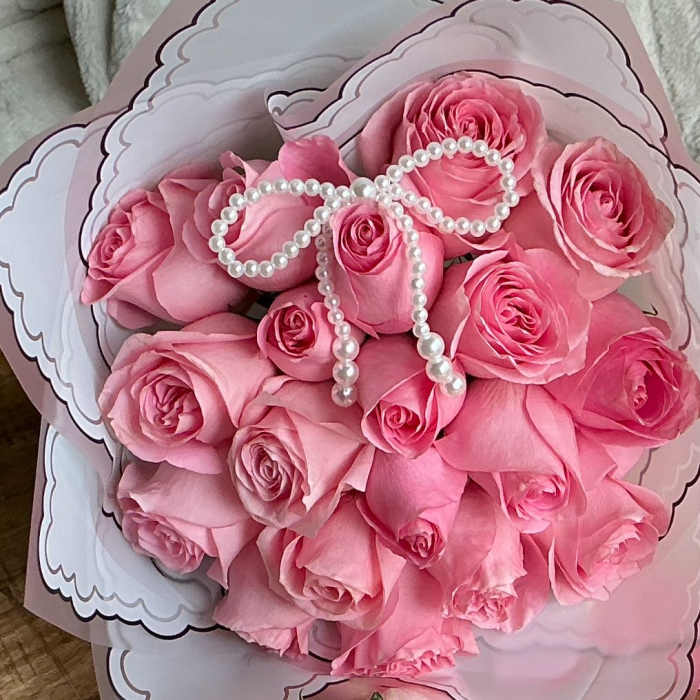 Bouquet of pink roses wrapped in decorative paper with a pearl bow
