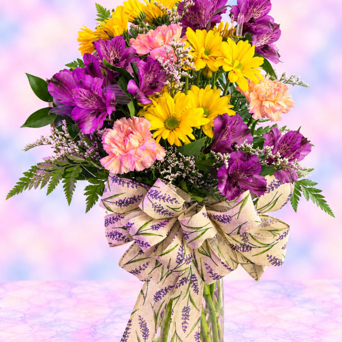 Bouquet of yellow daisies, purple alstroemeria, and pink carnations in a glass vase