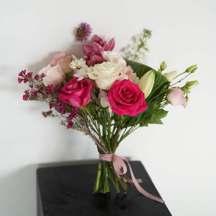 Bouquet of pink and white roses with mixed blooms tied with a pink ribbon