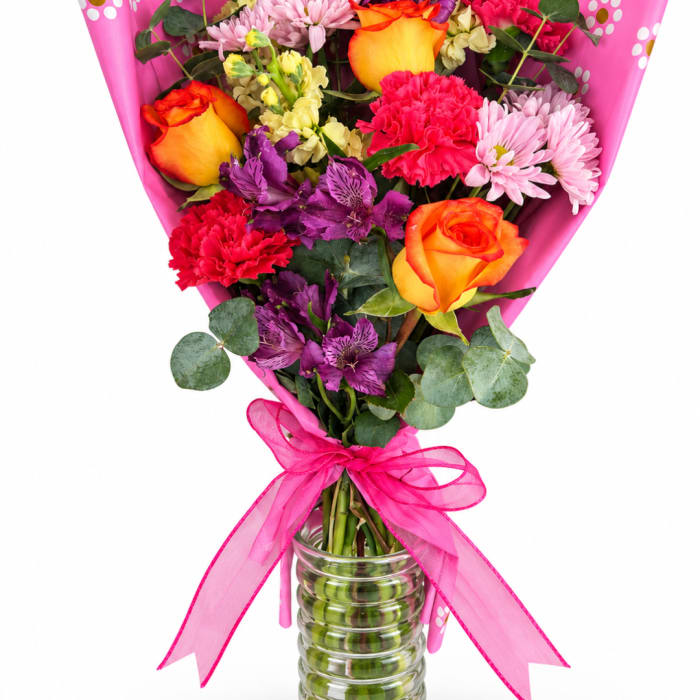 Bouquet of mixed flowers in a glass vase with a pink ribbon