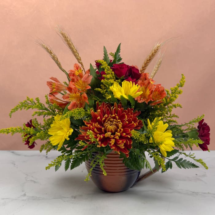 Mixed bouquet in a copper mug with red, yellow, and orange flowers