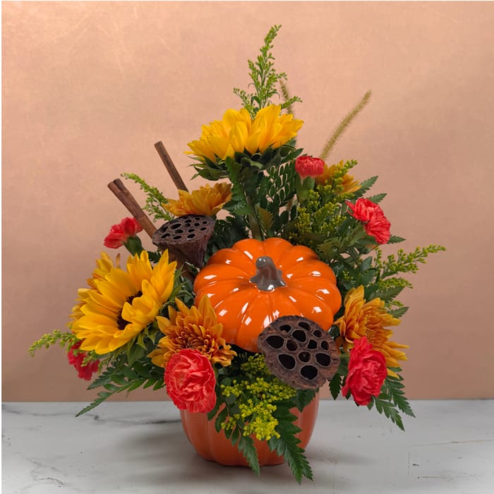 Pumpkin centerpiece with yellow sunflowers and red carnations in a vase