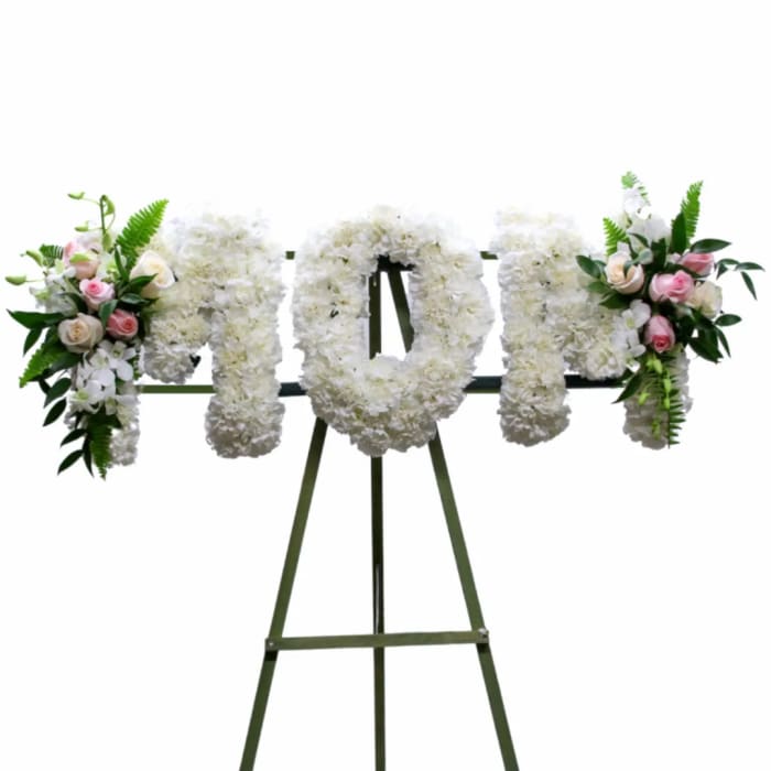 White floral standing tribute on an easel with pink rose accents