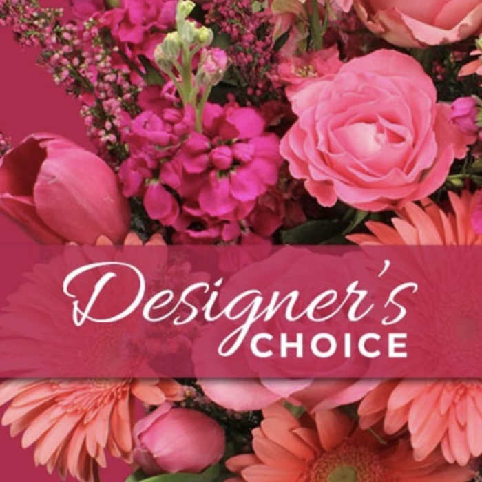 Bright pink and coral arrangement with roses, gerbera daisies and tulips with 'Designer’s Choice' text overlay.