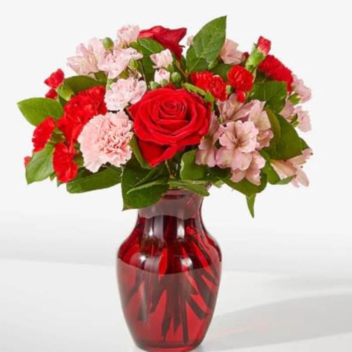 Red roses and pink carnations in a red glass vase