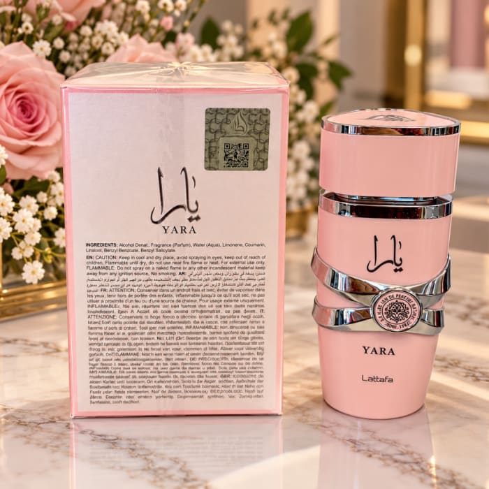 Pink perfume bottle and matching box beside pink roses