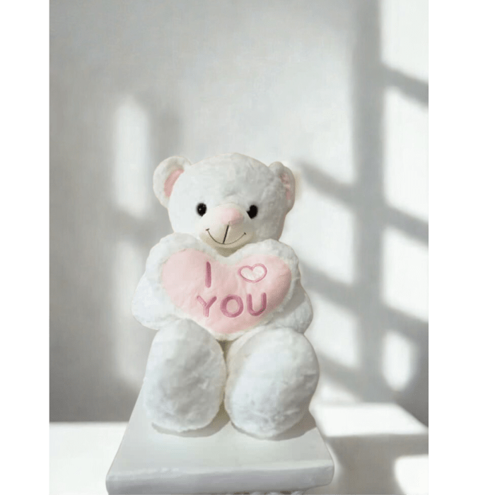 White teddy bear holding a pink heart that says I love you